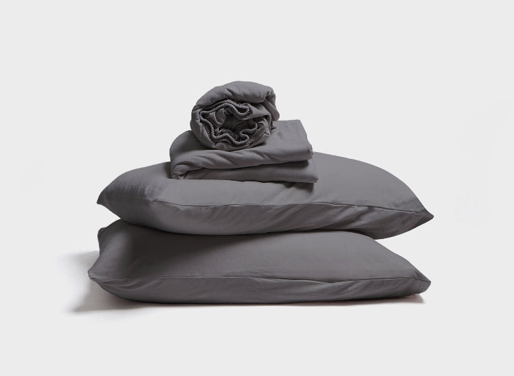 It-Fits jersey sheet set displayed as a stack of fitted sheet, flat sheet and a pillow with pillowcase in charcoal grey colour 