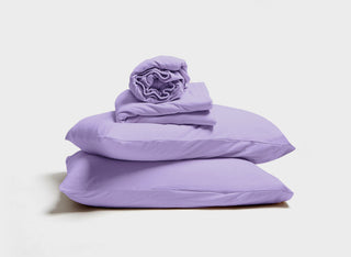 Lavender purple jersey sheet set by It-Fits, with a stack of pillow, pillowcase, fitted sheet, and flat sheet, featuring deep pockets for adjustable beds against a neutral backdrop.