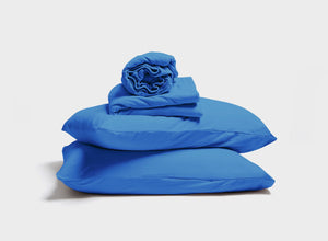 Royal blue jersey sheet set by It-Fits, with a stack of pillow, pillowcase, fitted sheet, and flat sheet, showcasing deep pockets for adjustable beds on a plain background.