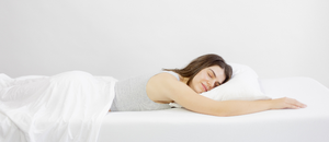 woman lying on her stomach comfortably sleeping with it-fits jersey sheet set in colour white